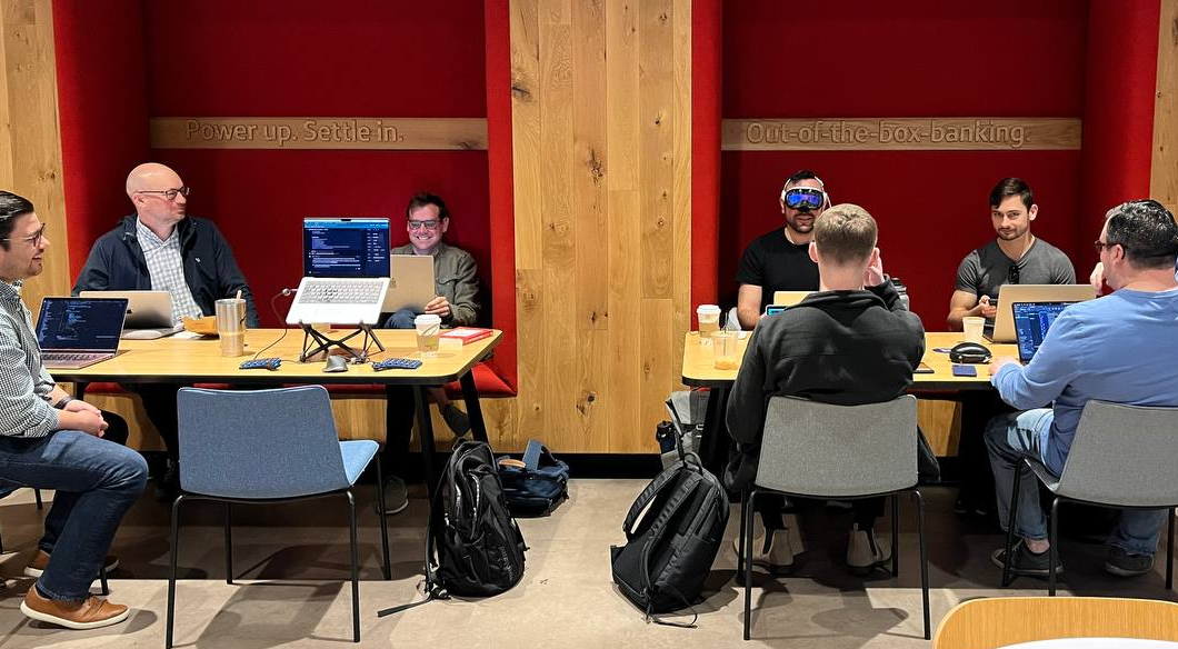 Group of men working from laptops in coffee shop.